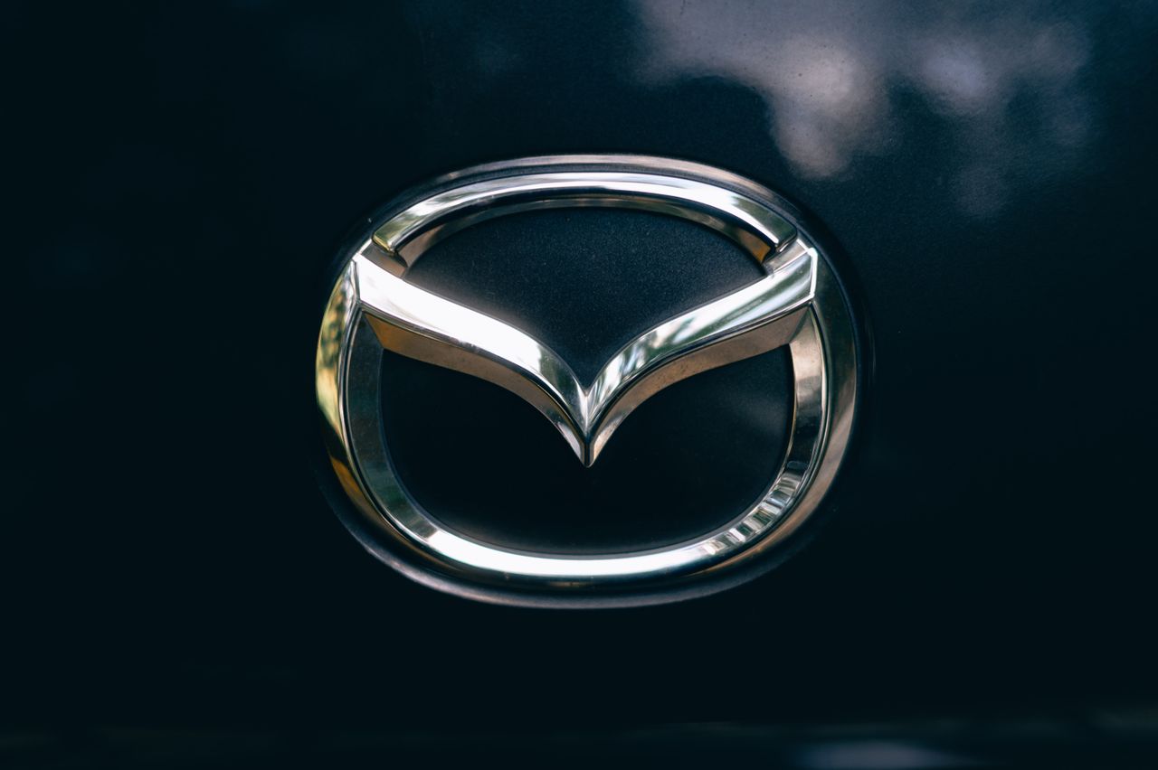 Close-up of a shiny metallic car logo on a dark surface.